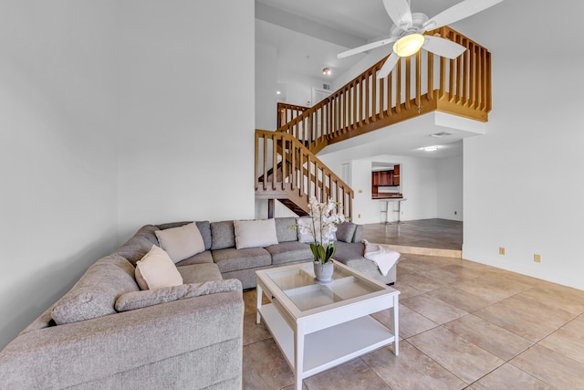 living room featuring light tile patterned floors, ceiling fan, and a high ceiling