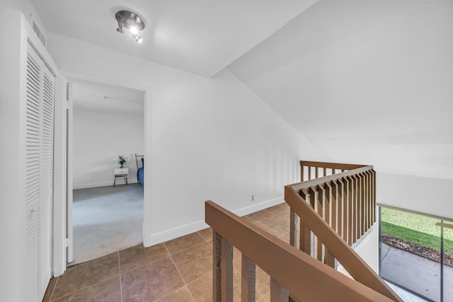 hall with tile patterned floors and vaulted ceiling