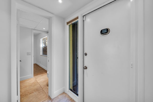 hall featuring light tile patterned floors and a drop ceiling