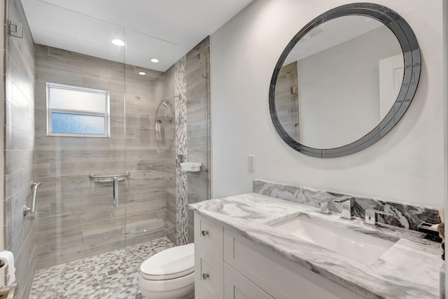 bathroom with vanity, a shower with door, and toilet