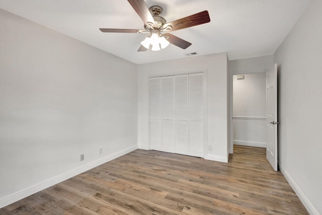 unfurnished bedroom featuring dark wood-type flooring, a textured ceiling, ceiling fan, and a closet