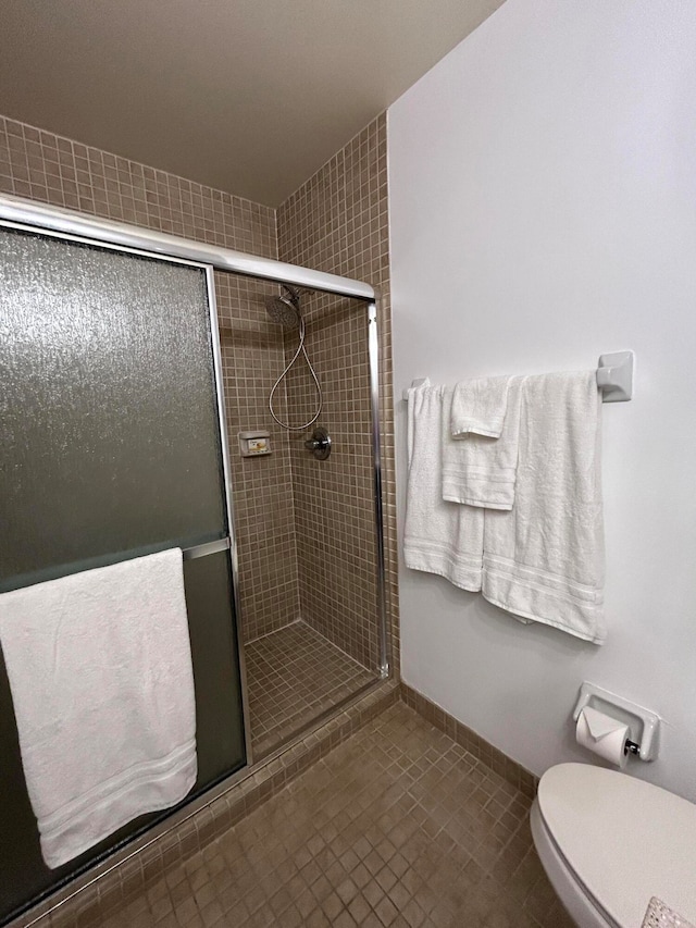 bathroom with tile patterned flooring, an enclosed shower, and toilet