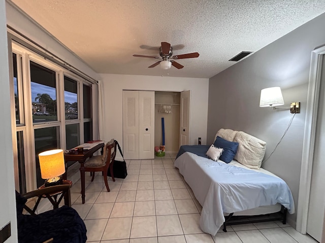 tiled bedroom with a textured ceiling, a closet, and ceiling fan