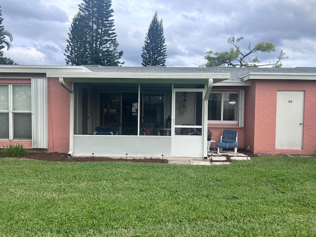 back of property with a yard and a sunroom