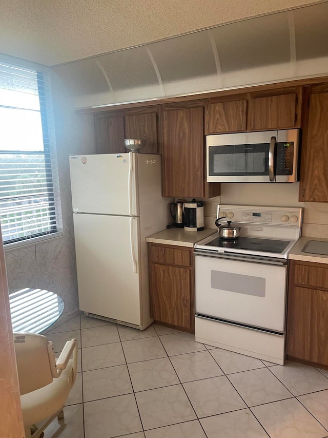 kitchen featuring a textured ceiling, white appliances, and light tile patterned floors