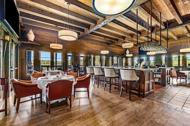 dining space featuring wood walls, beamed ceiling, hardwood / wood-style flooring, and wooden ceiling