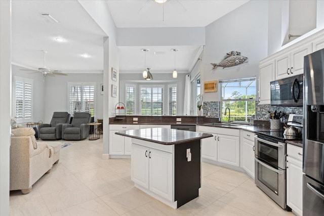 kitchen featuring ceiling fan, decorative backsplash, stainless steel appliances, and a sink