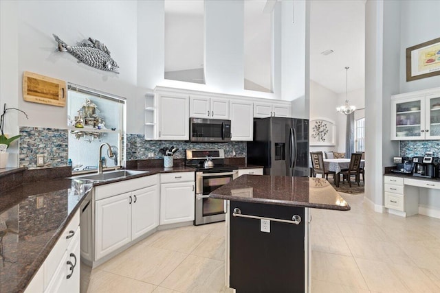 kitchen with stainless steel appliances, a sink, a chandelier, white cabinetry, and high vaulted ceiling