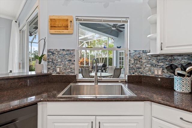 kitchen with sink, white cabinets, decorative backsplash, dark stone countertops, and ceiling fan