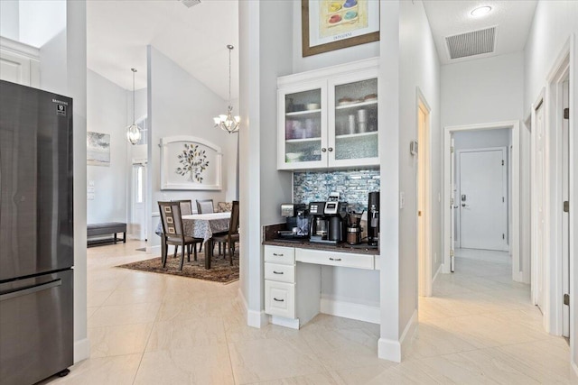 kitchen with stainless steel fridge, decorative light fixtures, high vaulted ceiling, and white cabinets