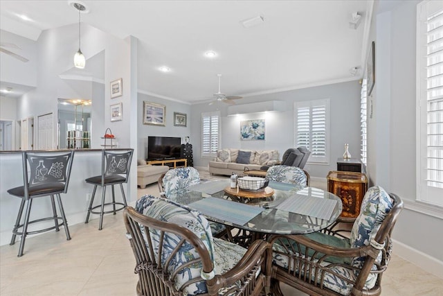 dining room with baseboards, ornamental molding, ceiling fan, and a healthy amount of sunlight