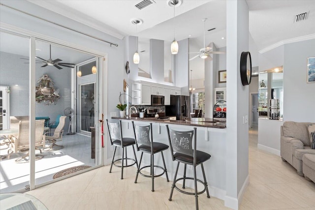 kitchen with pendant lighting, white cabinetry, kitchen peninsula, stainless steel appliances, and ceiling fan