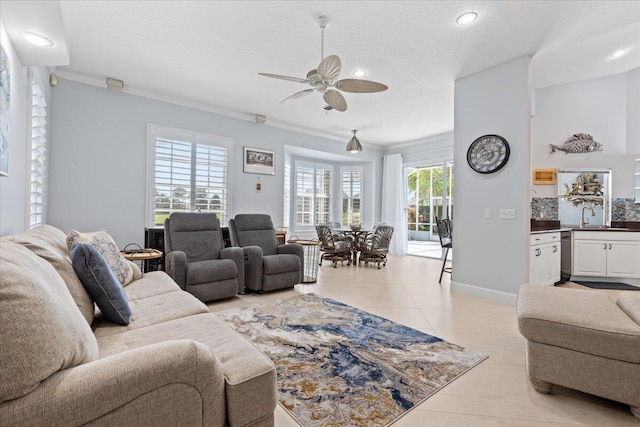 living room featuring ceiling fan, light tile patterned flooring, ornamental molding, and a healthy amount of sunlight