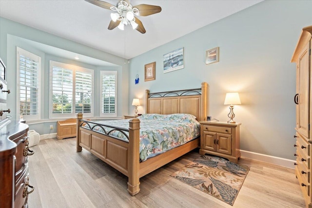 bedroom with light wood-type flooring, a ceiling fan, and baseboards