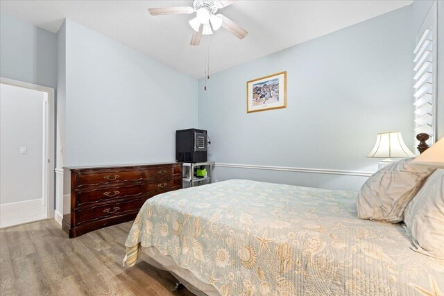 bedroom with baseboards, a ceiling fan, wood finished floors, and vaulted ceiling