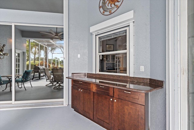 bar with a textured wall and a ceiling fan