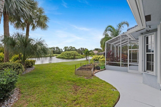 view of yard with glass enclosure, a patio area, a garden, and a water view