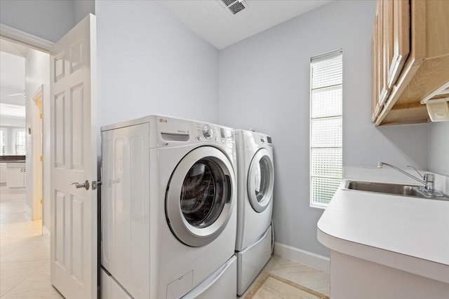 clothes washing area with cabinets, washing machine and clothes dryer, light tile patterned floors, and sink