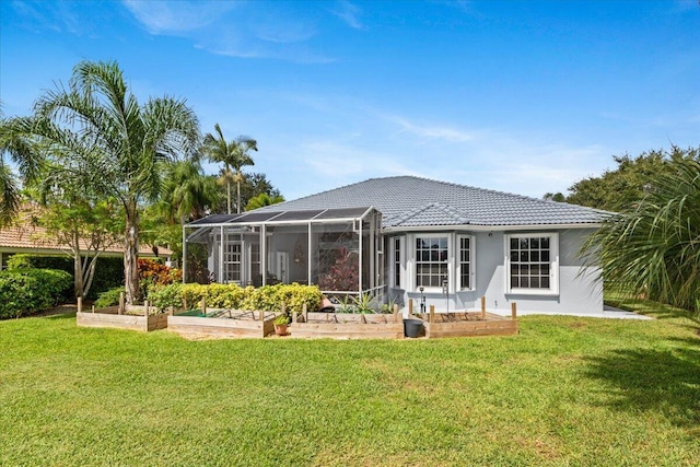 rear view of house with stucco siding, a yard, a garden, and a tile roof