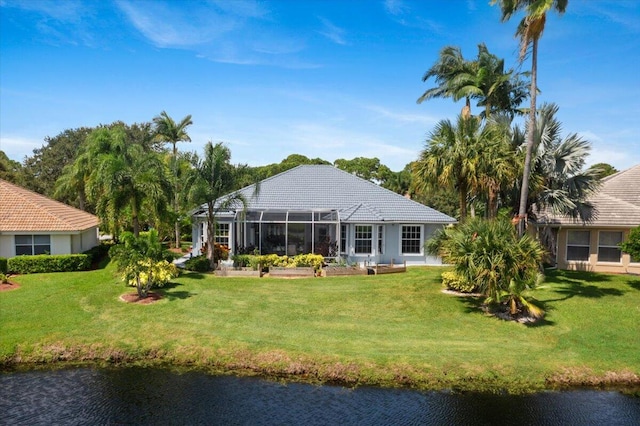 back of property featuring glass enclosure, a yard, a tile roof, and a water view
