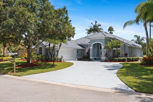 view of front of home featuring a garage, a tile roof, a front yard, and driveway