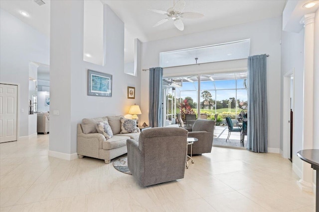 living room featuring ceiling fan, a high ceiling, tile patterned flooring, and baseboards