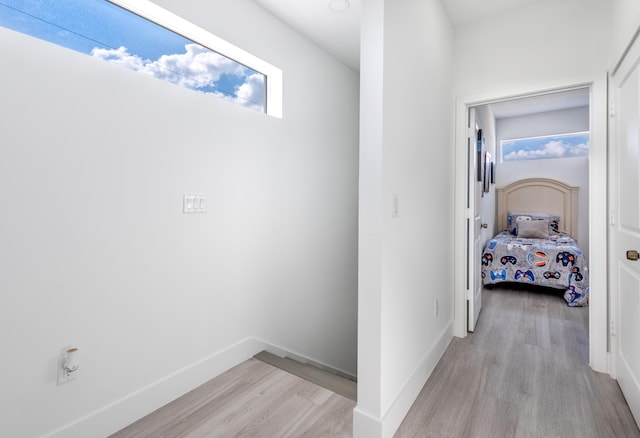 corridor featuring light wood-style flooring and baseboards