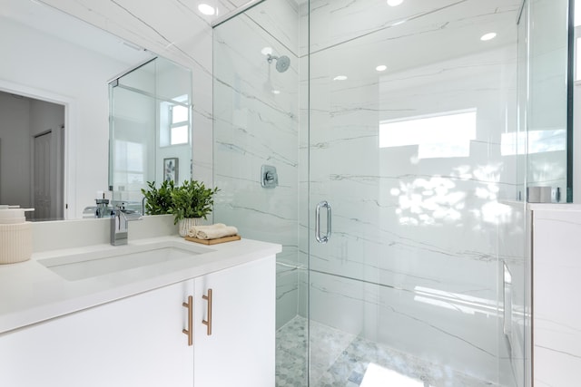 bathroom featuring a marble finish shower and vanity