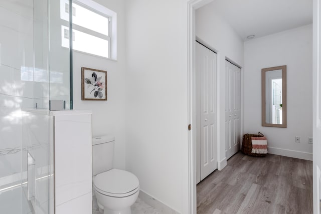 bathroom featuring a marble finish shower, toilet, a closet, and wood finished floors