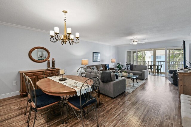 dining space with ceiling fan with notable chandelier, ornamental molding, and dark wood-type flooring