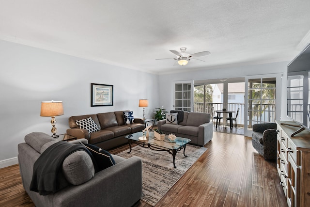 living room with a textured ceiling, ceiling fan, dark hardwood / wood-style floors, and crown molding