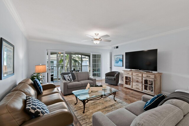 living room featuring wood-type flooring, ceiling fan, and crown molding