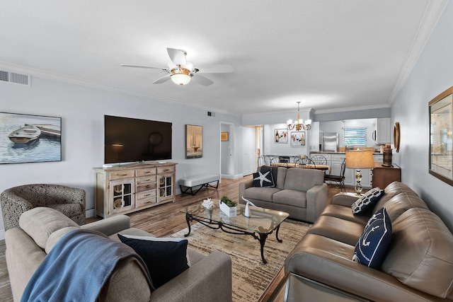 living room featuring ceiling fan with notable chandelier, hardwood / wood-style floors, and crown molding