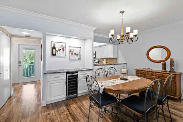 dining area featuring ornamental molding, beverage cooler, dark hardwood / wood-style floors, and a notable chandelier