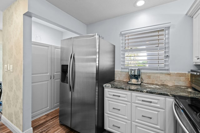 kitchen featuring dark wood-type flooring, white cabinets, backsplash, appliances with stainless steel finishes, and dark stone countertops