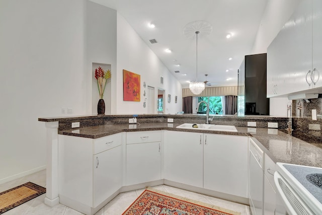 kitchen with white cabinetry, dark stone countertops, sink, and decorative light fixtures