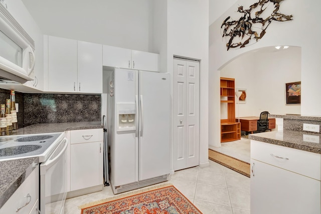 kitchen with decorative backsplash, light tile patterned floors, white cabinetry, high vaulted ceiling, and white appliances