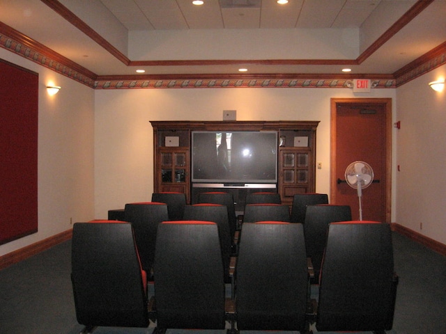 home theater room with ornamental molding and a tray ceiling