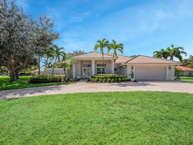 mediterranean / spanish home featuring a garage and a front lawn