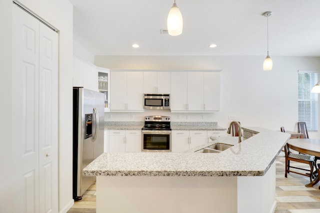 kitchen featuring white cabinetry, sink, light hardwood / wood-style floors, pendant lighting, and appliances with stainless steel finishes