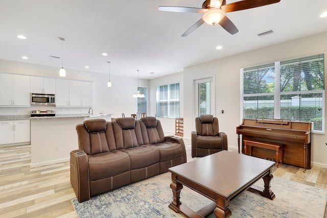 living room with light hardwood / wood-style flooring, ceiling fan, and sink