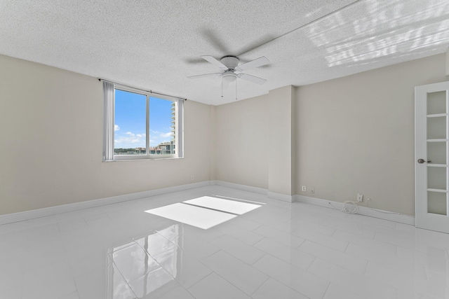 spare room featuring ceiling fan, a textured ceiling, and light tile patterned floors