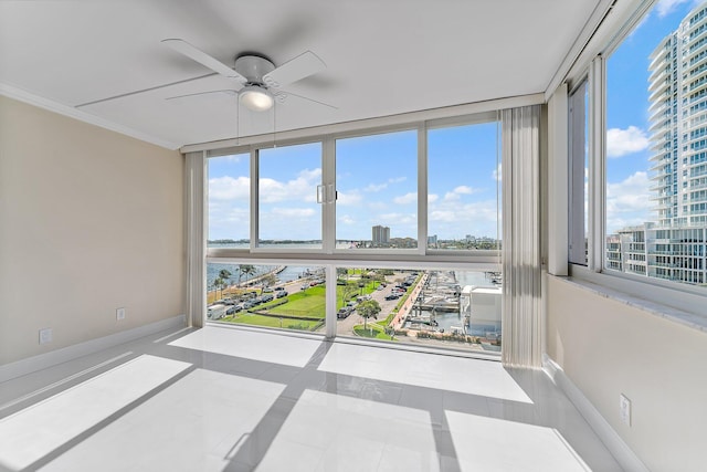 unfurnished sunroom featuring ceiling fan and a water view