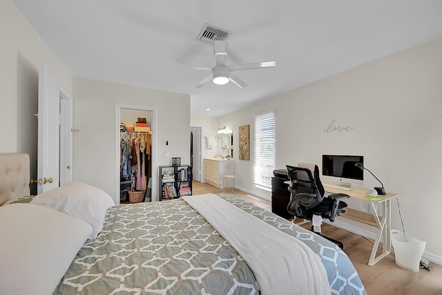 bedroom featuring ensuite bath, ceiling fan, a spacious closet, a closet, and light wood-type flooring