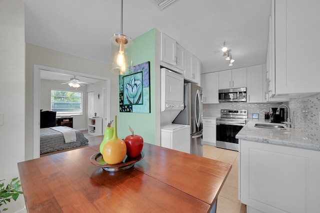 kitchen featuring sink, stainless steel appliances, light tile patterned floors, tasteful backsplash, and white cabinets