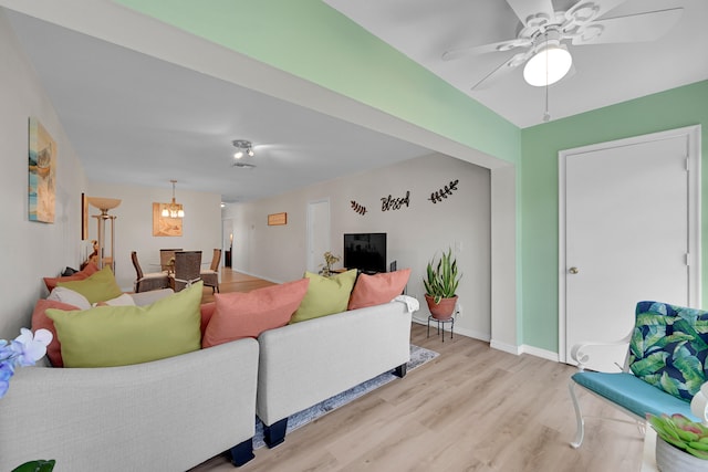 living room with ceiling fan with notable chandelier and light hardwood / wood-style floors