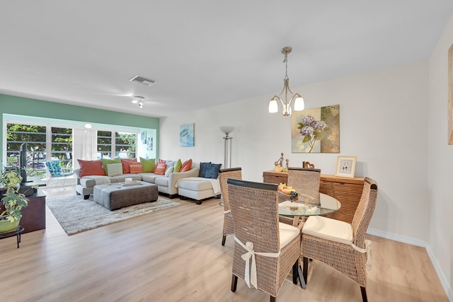 dining room featuring light wood-type flooring and a notable chandelier