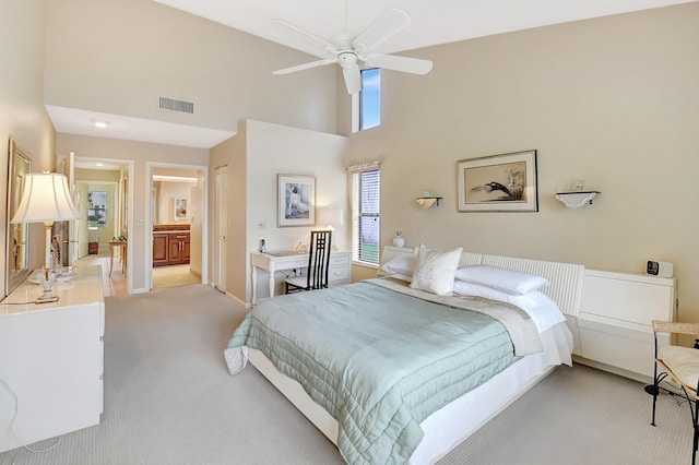 bedroom featuring a closet, light carpet, ceiling fan, a high ceiling, and connected bathroom