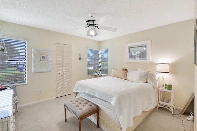 bedroom featuring a closet, ceiling fan, light carpet, and a textured ceiling