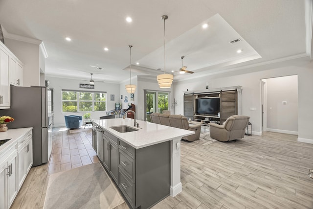 kitchen featuring an island with sink, white cabinets, pendant lighting, ceiling fan, and sink